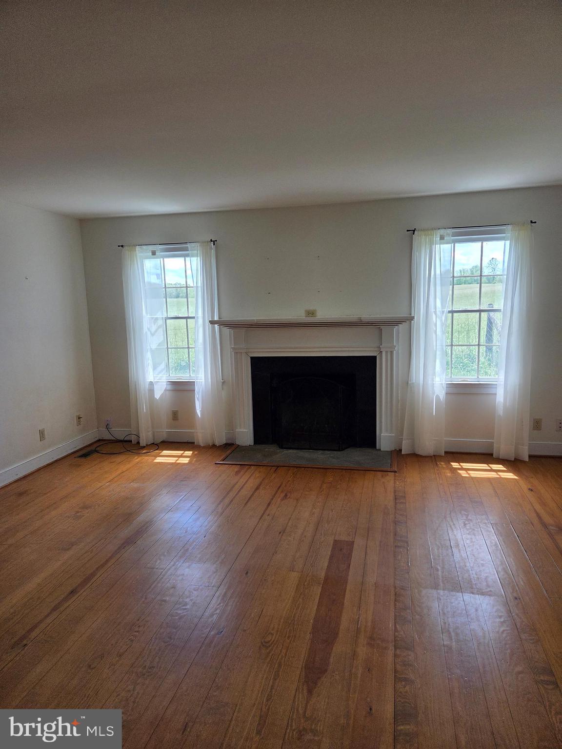 2565 Crenshaw Road Marshall, VA 20115 - Photo 6 of 14 an empty room with wooden floor fireplace and windows