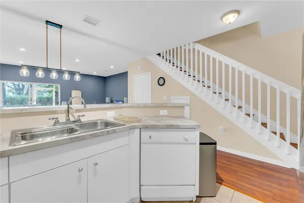 a kitchen with granite countertop a sink and white cabinets next to a window