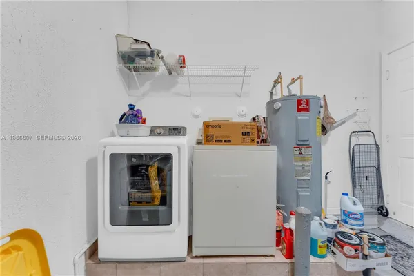 a utility room with fridge dryer and washer