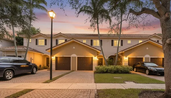 a view of a white house with a large space and a yard