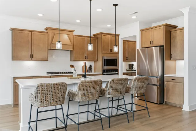 a kitchen with stainless steel appliances granite countertop a refrigerator a stove a sink dishwasher a dining table and chairs with wooden floor
