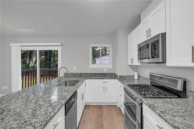 a kitchen with granite countertop a sink stove and cabinets