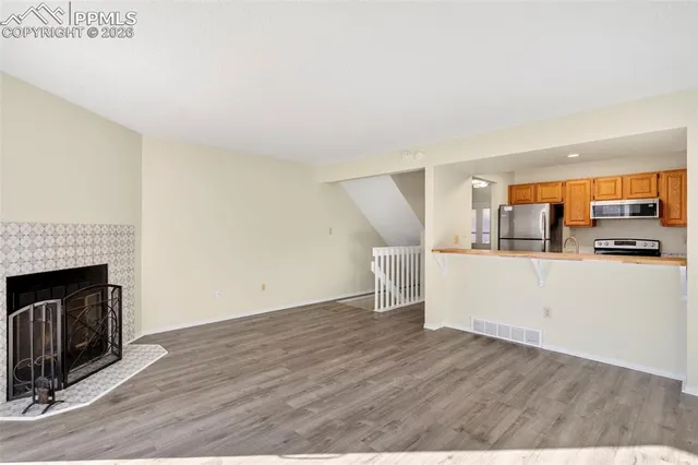 a view of a kitchen with wooden floor and a fireplace