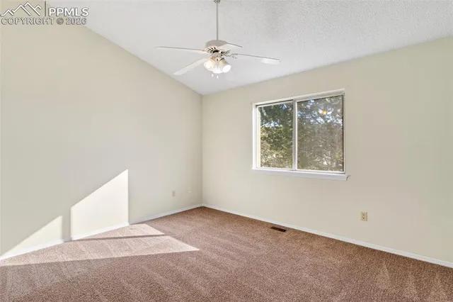 an empty room with a window and a fan