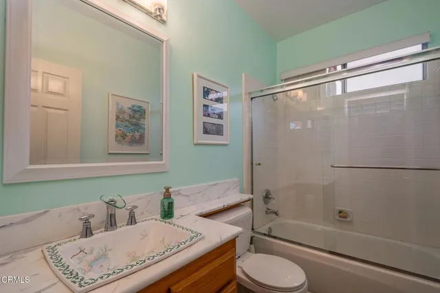a bathroom with a granite countertop bathtub shower sink vanity and toilet