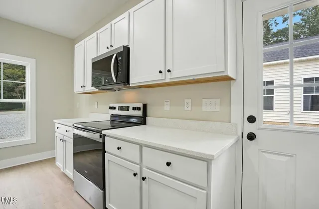 a kitchen with white cabinets stainless steel appliances and window