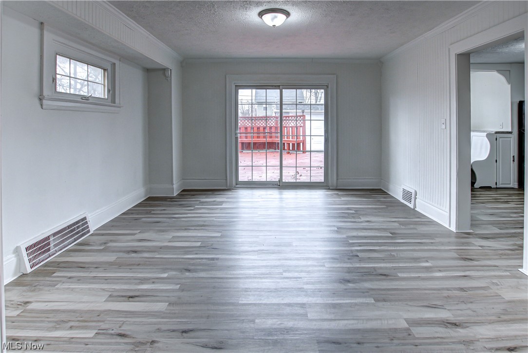 4764 Rockwood Road Cleveland, OH 44125 - Photo 12 of 35 Unfurnished room with light wood-type flooring, a textured ceiling, and crown molding