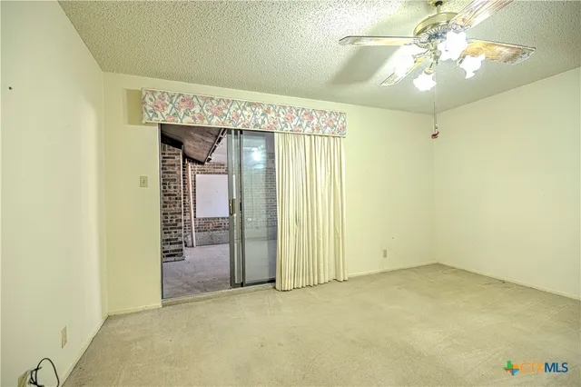 an empty room with a chandelier fan and a window