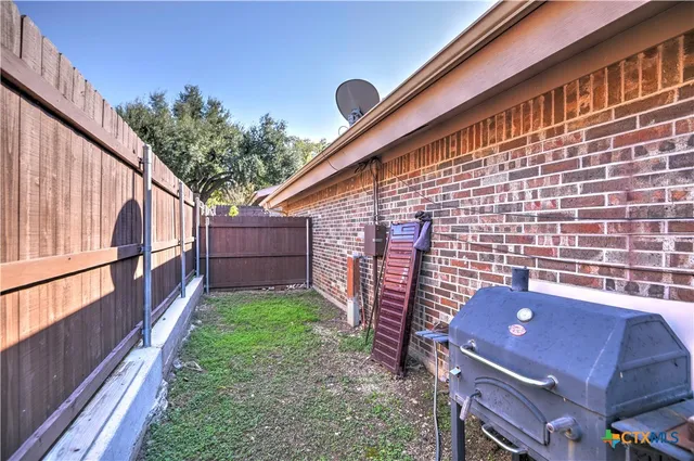 a backyard of a house with wooden fence and large trees