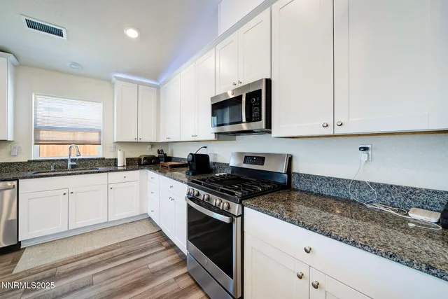 a kitchen with granite countertop white cabinets stainless steel appliances and a sink