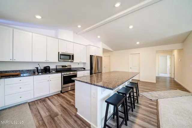 a kitchen with granite countertop white cabinets and stainless steel appliances