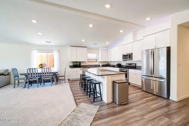 a kitchen with a refrigerator a dining table and chairs
