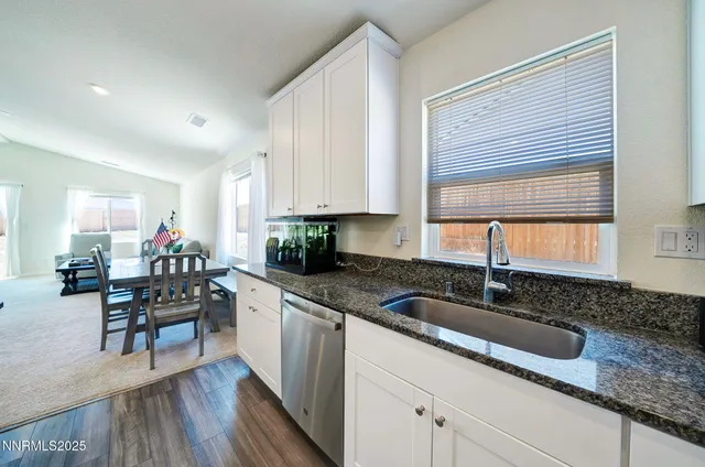 a kitchen with granite countertop a sink white cabinets and window