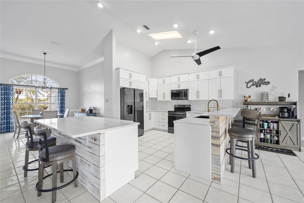 474 Orlando Boulevard Port Charlotte, FL 33954 - Photo 12 of 36 a kitchen with stainless steel appliances kitchen island granite countertop a table chairs and a refrigerator