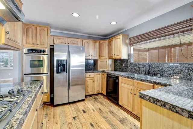 a kitchen with stainless steel appliances granite countertop a refrigerator a stove and a sink