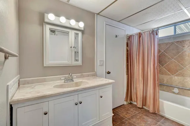 a bathroom with a sink vanity granite tub and shower