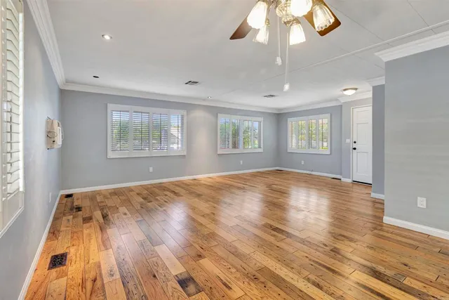 a view of empty room with wooden floor and fan