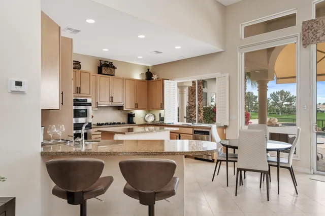 a kitchen with stainless steel appliances granite countertop a stove a sink a refrigerator and white cabinets with wooden floor