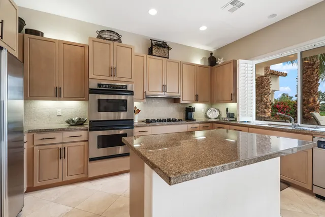 a kitchen with granite countertop a stove sink and refrigerator
