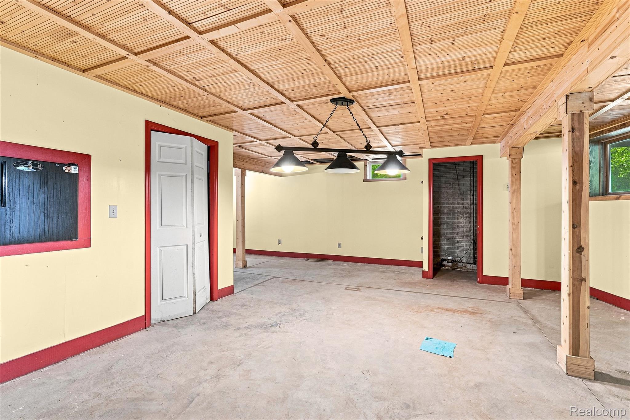 8340 North Nichols Road Flushing, MI 48433 - Photo 45 of 62 Wood-paneled ceiling with recessed square details, exposed wood support beams, concrete flooring, and an industrial-style chandelier