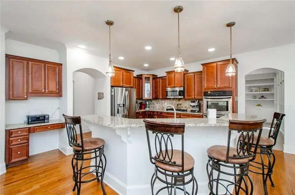 a living room with stainless steel appliances kitchen island granite countertop furniture and a wooden floor