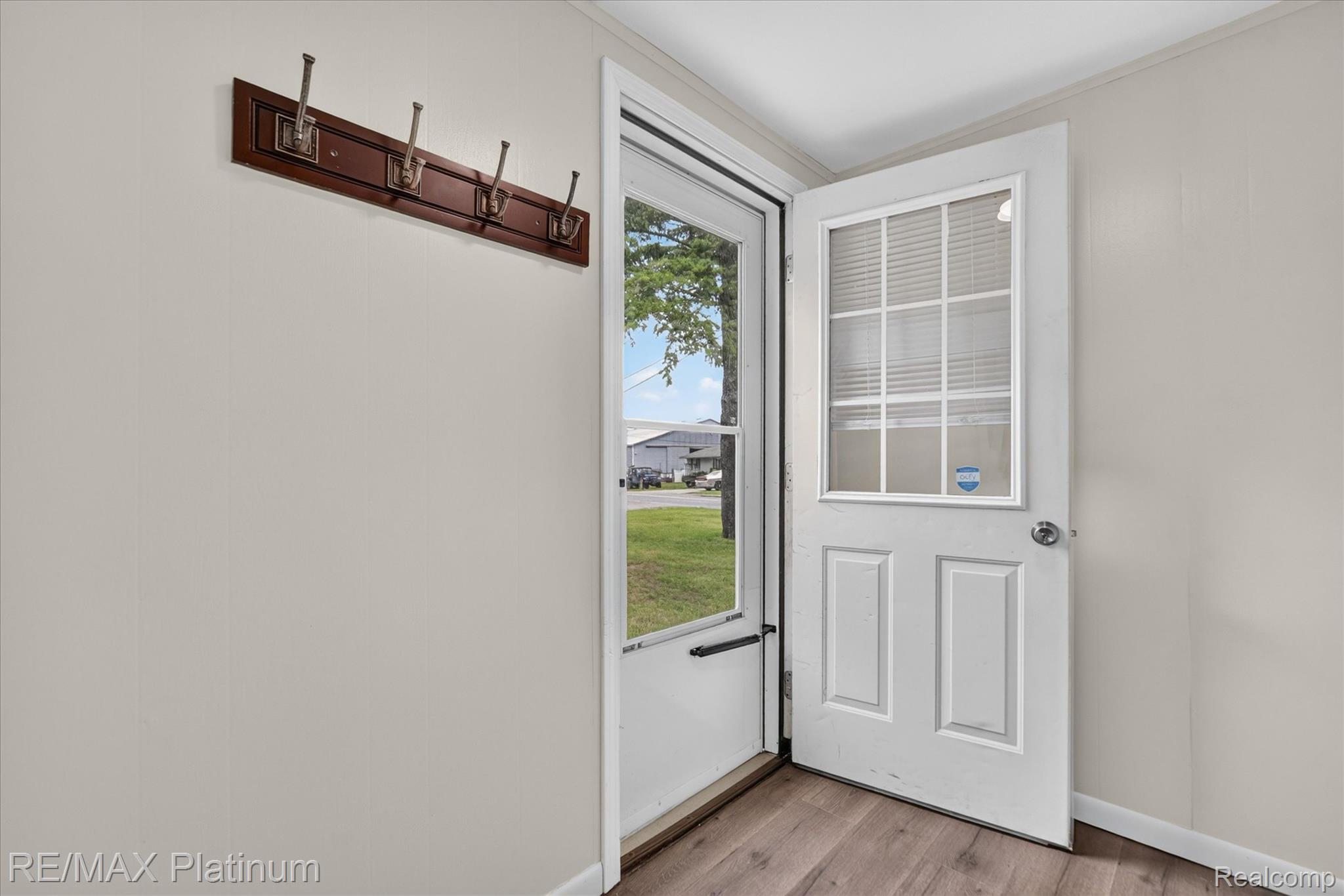 501 Kaiser Road Gregory, MI 48137 - Photo 5 of 27 Entryway featuring a white paneled door with integrated blinds, wood-finish flooring, and light-toned wall paneling