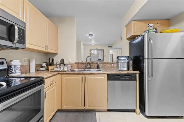 a kitchen with stainless steel appliances granite countertop a refrigerator a stove a sink and white cabinets