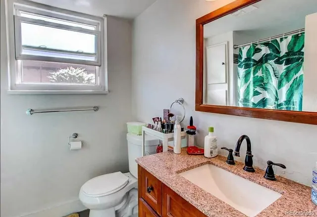 a bathroom with a granite countertop sink a large mirror and a toilet