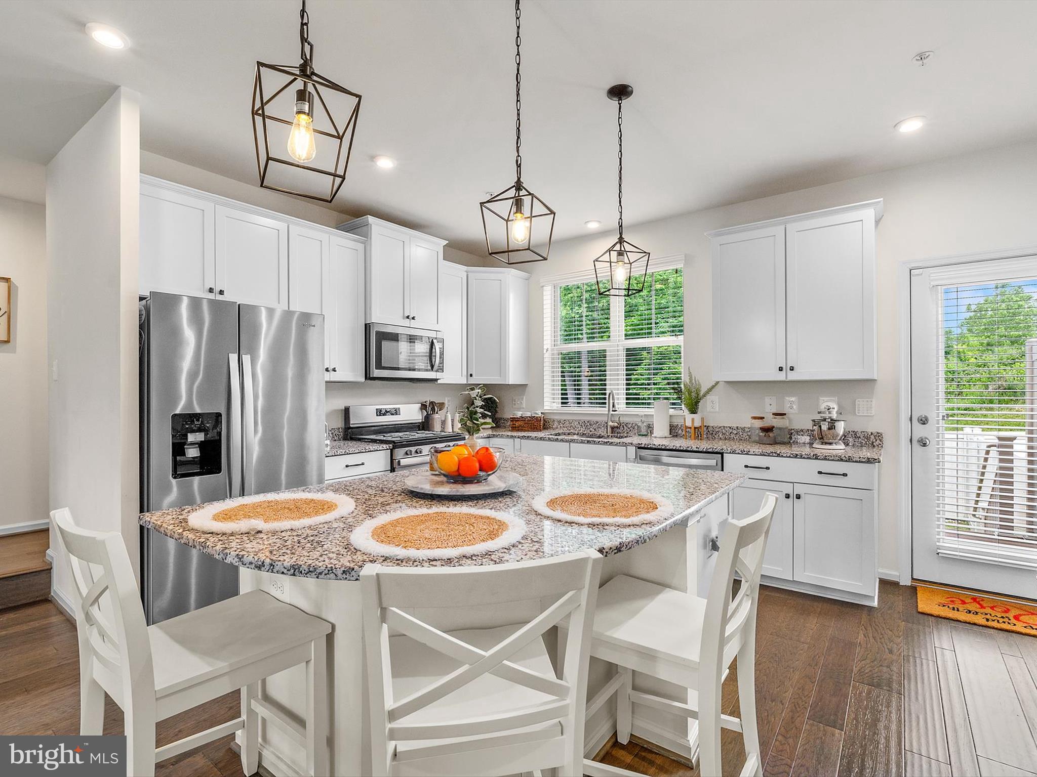 3058 Bretons Ridge Way Hanover, MD 21076 - Photo 13 of 43 a kitchen with stainless steel appliances a dining table chairs stove refrigerator and microwave