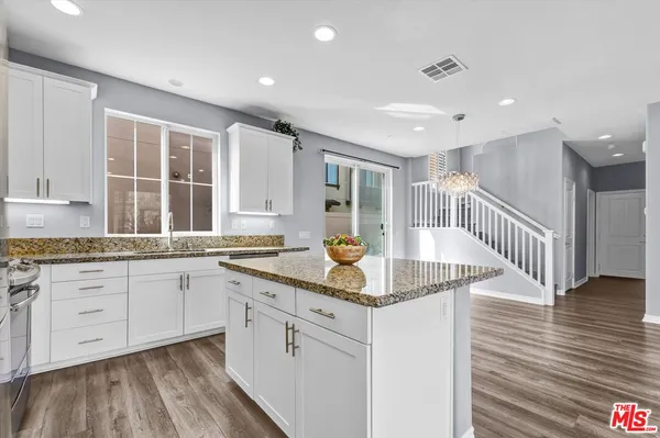 a kitchen with granite countertop white cabinets and white appliances