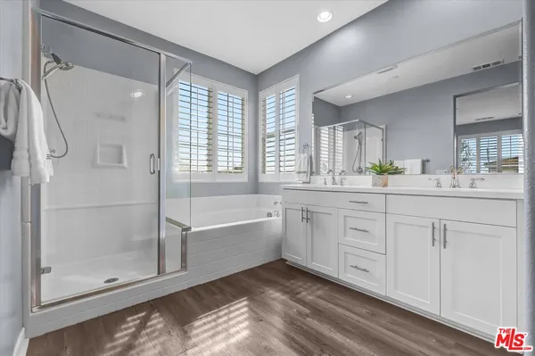 a spacious bathroom with a double vanity sink a large mirror and shower