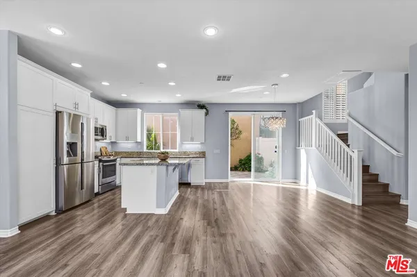 a kitchen with a refrigerator and wooden floor