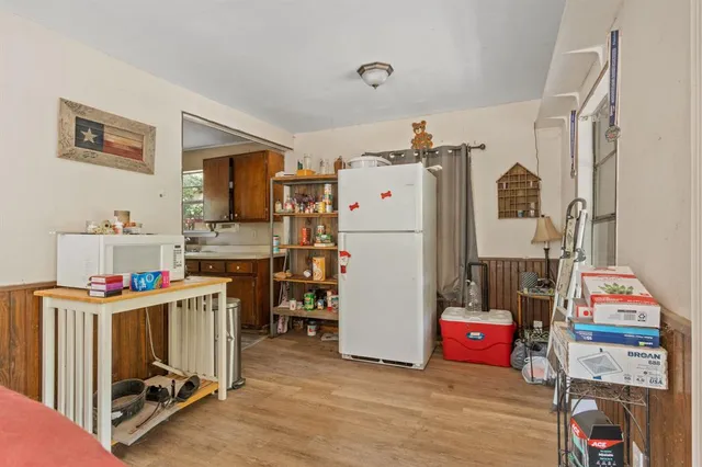 a storage room with fridge and wooden floor