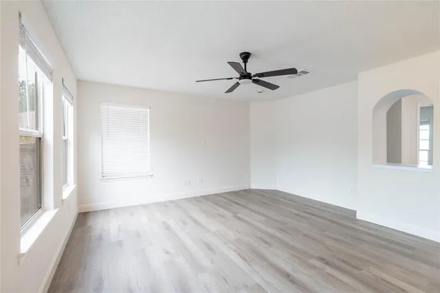 a view of empty room with wooden floor and fan