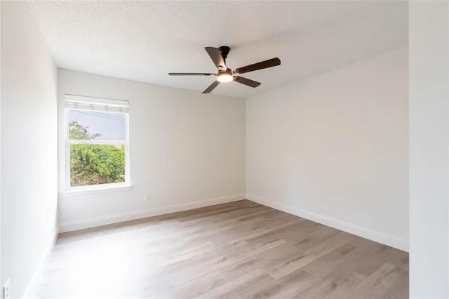 an empty room with a window and a fan
