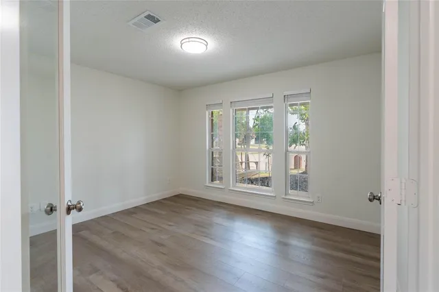 an empty room with wooden floor and windows