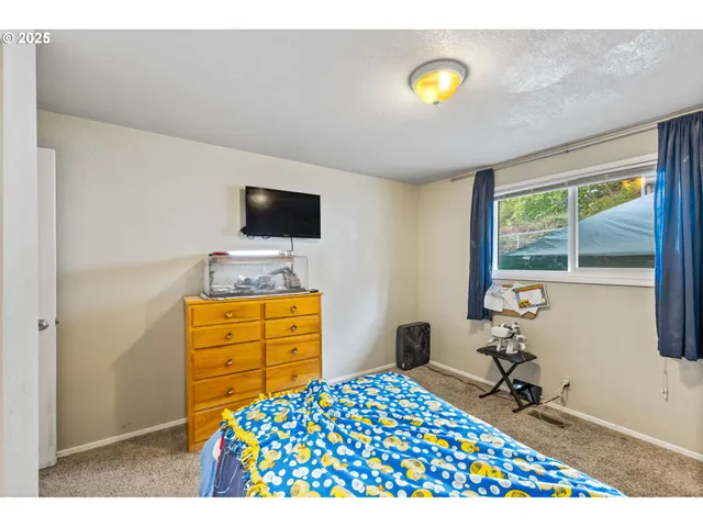 a bedroom with a bed and a flat tv screen on dresser