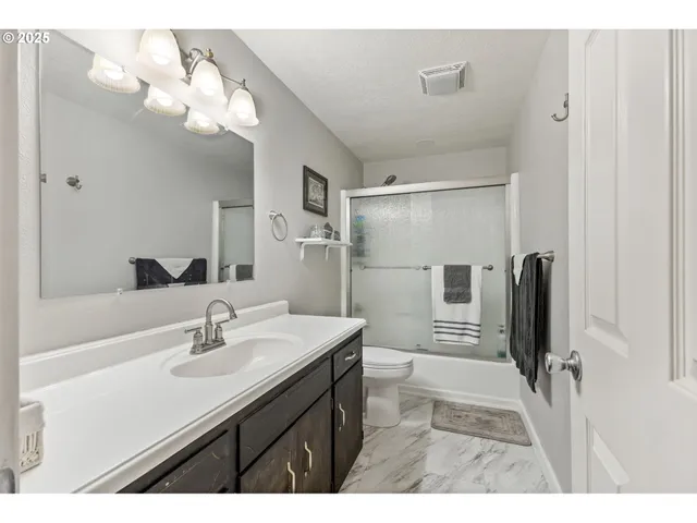 a bathroom with a sink a toilet a mirror and shower