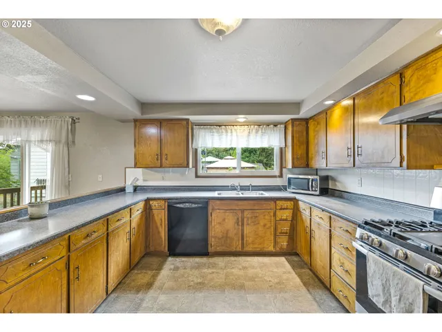 a large kitchen with stainless steel appliances granite countertop a sink and a stove