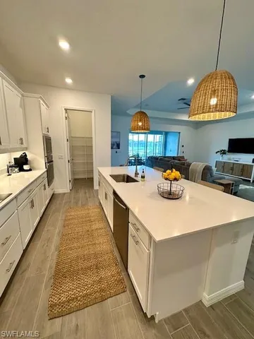 a kitchen with stainless steel appliances kitchen island granite countertop a sink a stove and a wooden floors