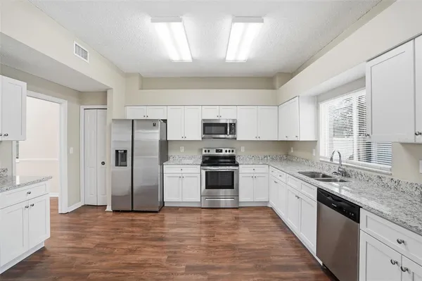 a large kitchen with stainless steel appliances kitchen island granite countertop a refrigerator and a sink