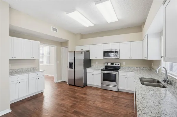 a kitchen with stainless steel appliances granite countertop a refrigerator and a stove top oven