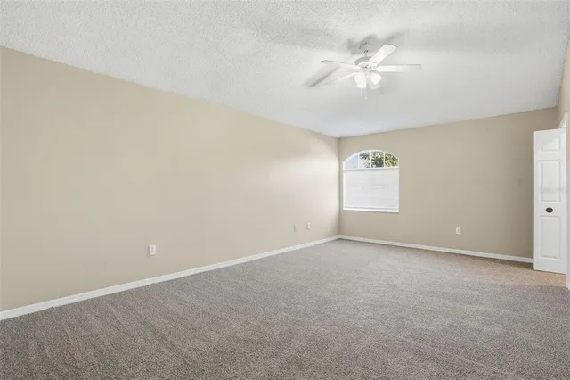 an empty room with windows and fan