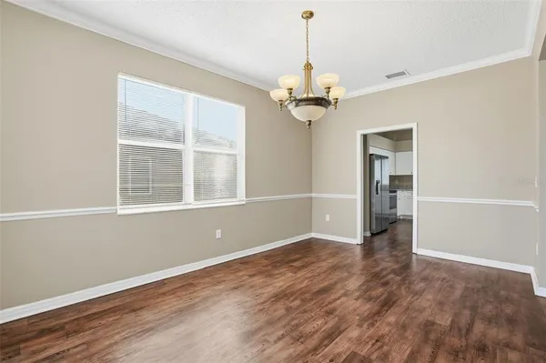 a view of empty room with wooden floor and chandelier