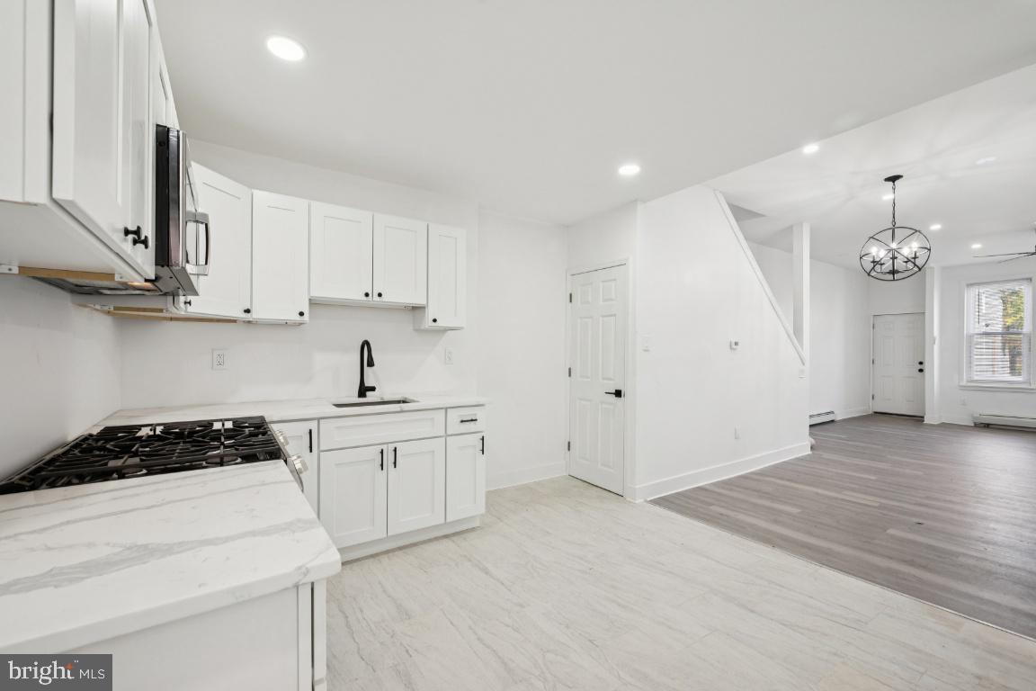718 Spruce Street Camden, NJ 08103 - Photo 22 of 39 a kitchen with granite countertop a stove a sink a refrigerator and white cabinets