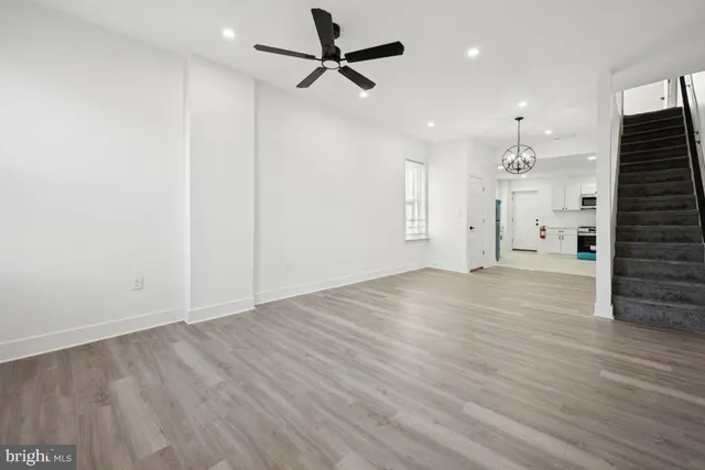 an empty room with wooden floor ceiling fan and windows