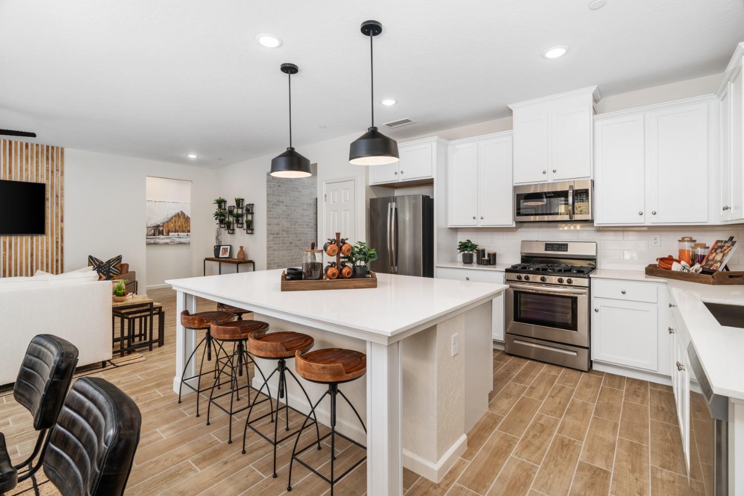 1150 Encore Way West Madera, CA 93636 - Photo 1 of 33 a kitchen with stainless steel appliances kitchen island granite countertop a stove a sink a microwave a dining table and chairs