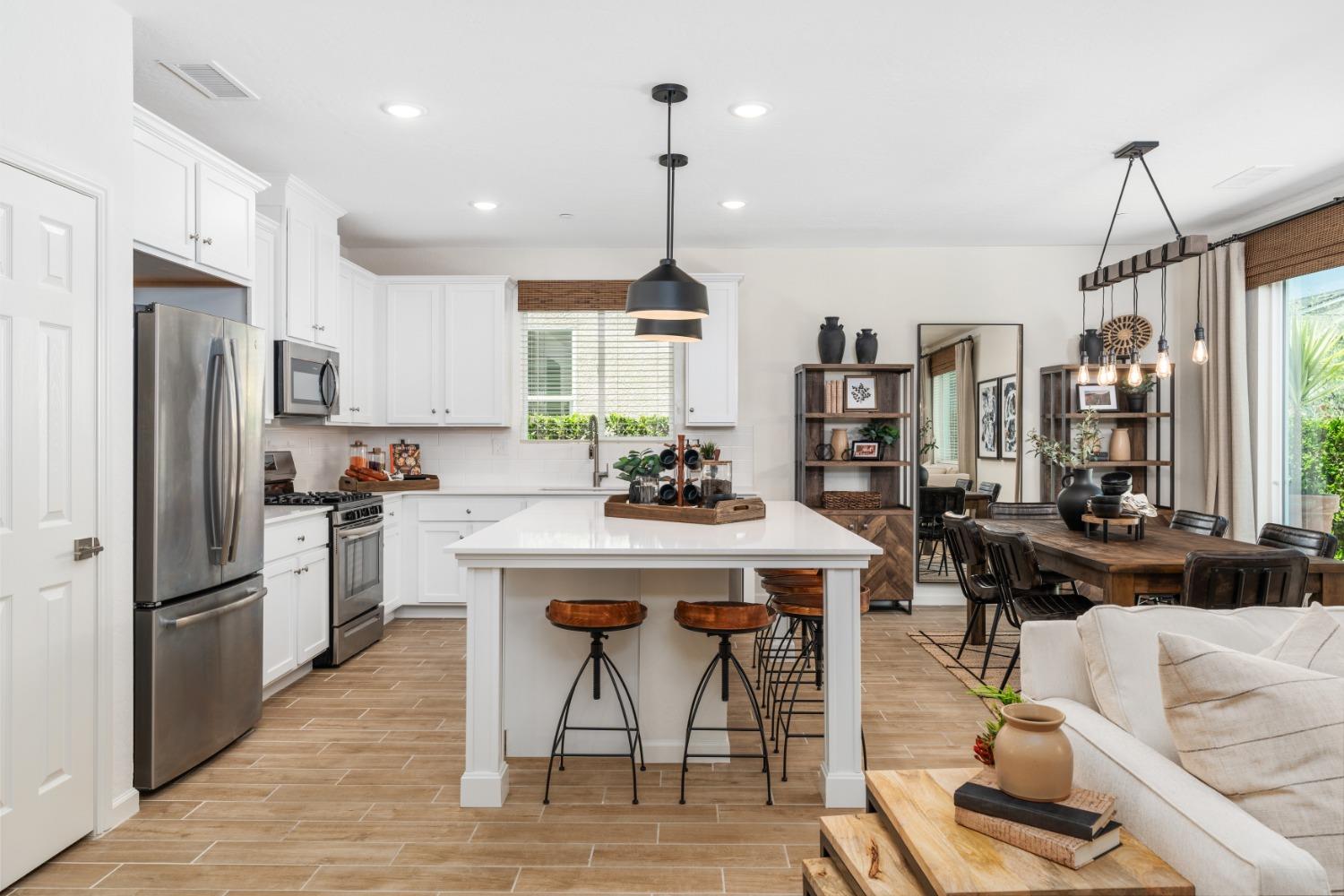 1150 Encore Way West Madera, CA 93636 - Photo 12 of 33 a kitchen with stainless steel appliances kitchen island granite countertop a dining table chairs and a refrigerator