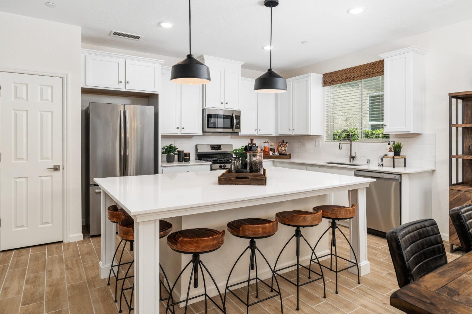 1150 Encore Way West Madera, CA 93636 - Photo 14 of 33 a kitchen with stainless steel appliances granite countertop a sink a stove a refrigerator and island with wooden floor