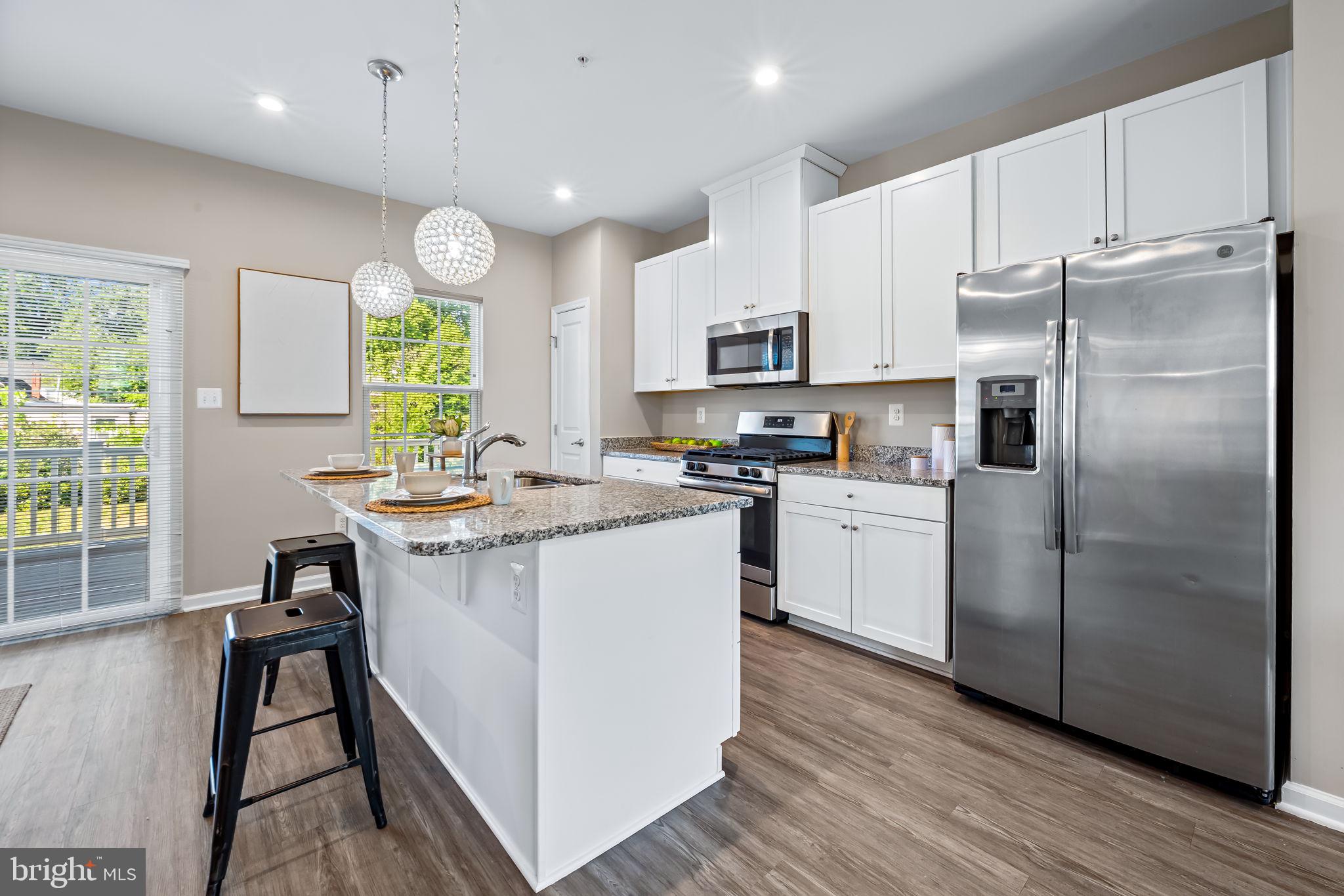 8206 Kirk Farm Circle Windsor Mill, MD 21244 - Photo 8 of 35 a kitchen with kitchen island granite countertop wooden floors stainless steel appliances a sink and a refrigerator